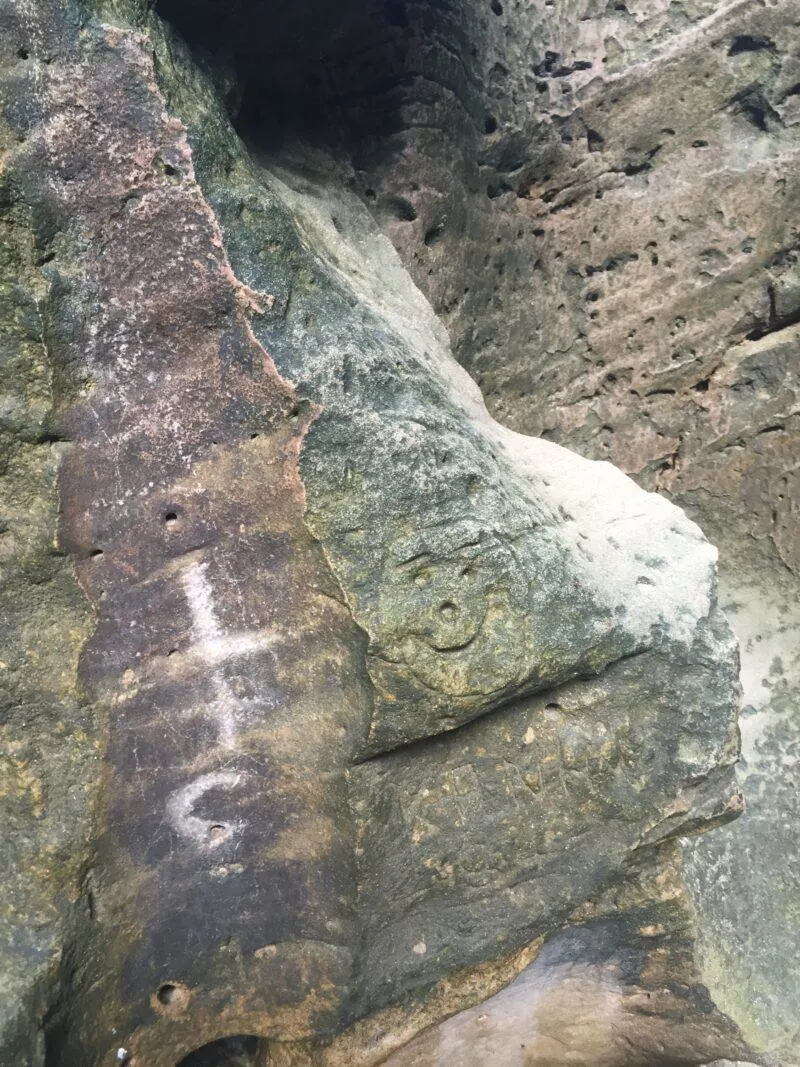 Smiling petroglyph carved on rock wall