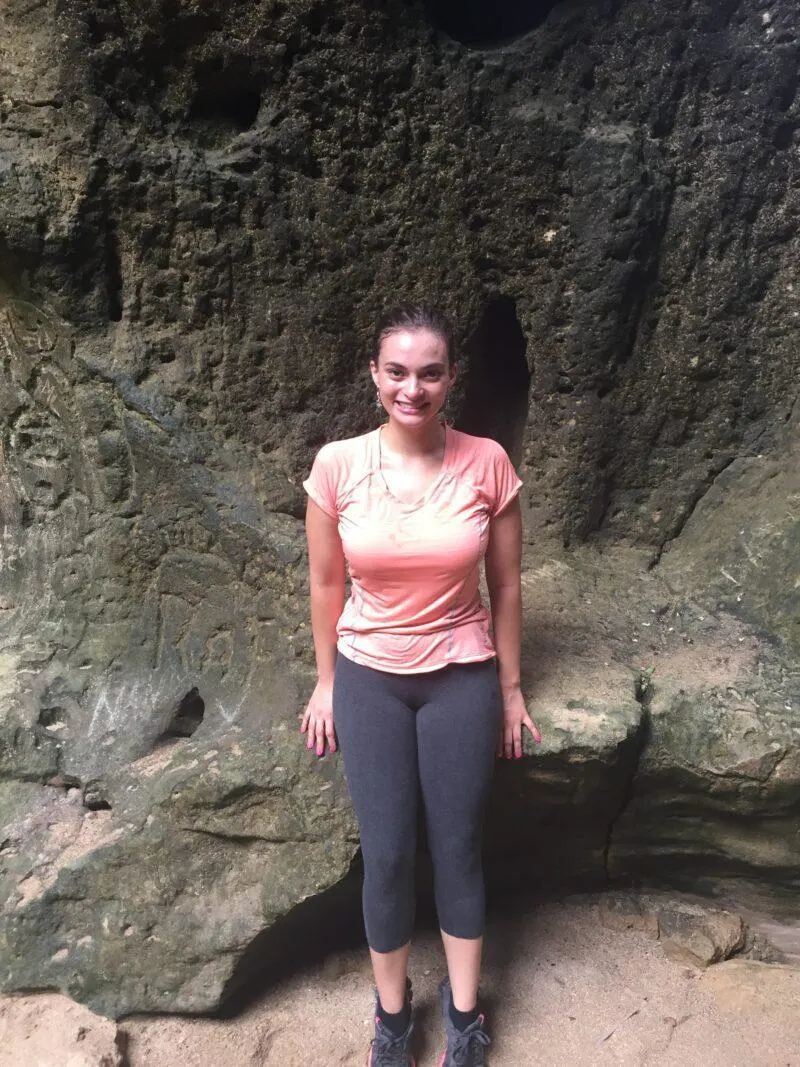 Woman standing in front of petroglyphs on wall