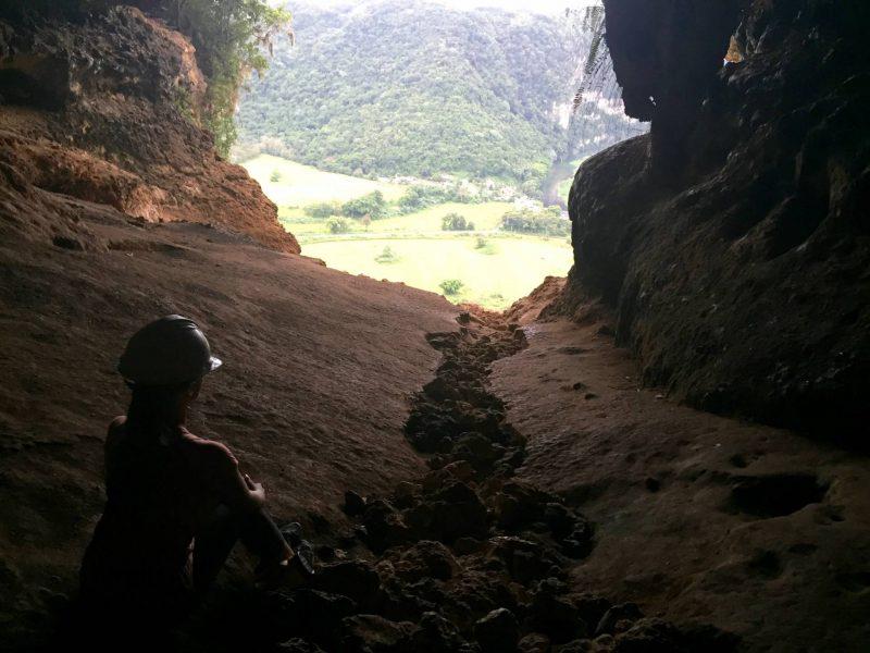 Woman sitting in front of cave opening 