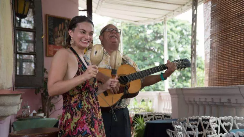 Woman dancing with maracas while man plays guitar