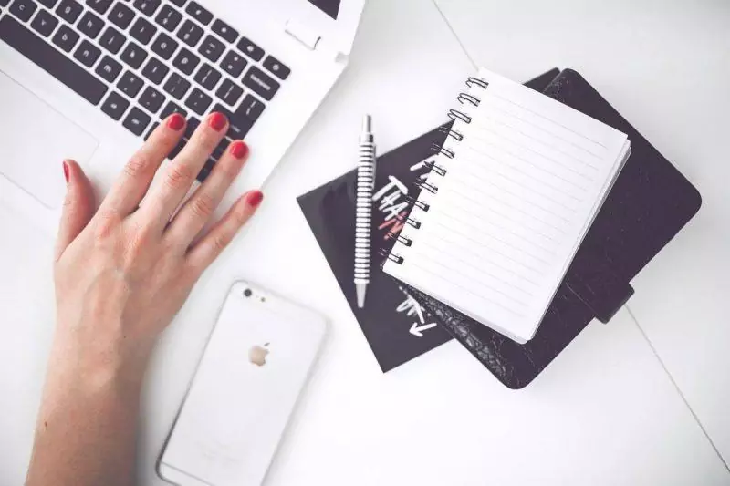 Woman at laptop with notebook nearby