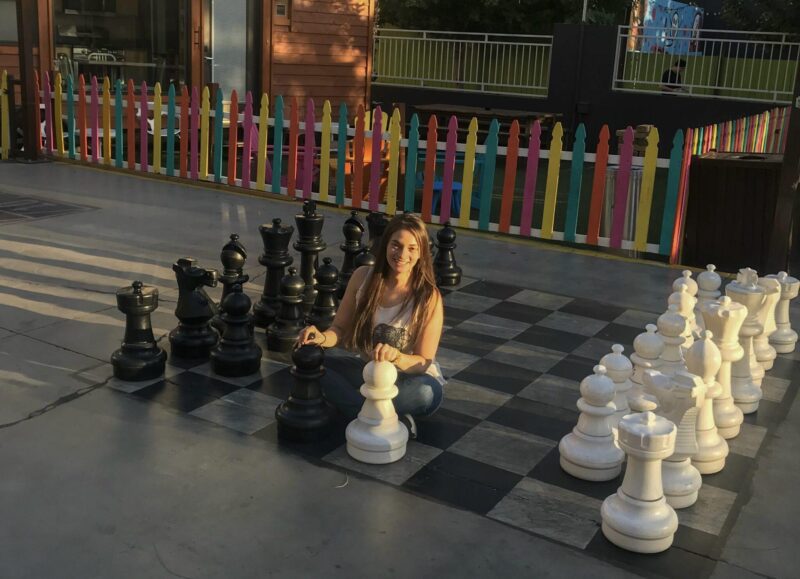 Woman sitting on life sized chess board