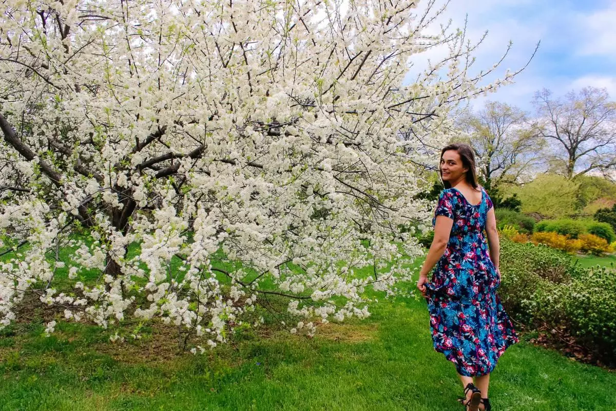 Girl standing next to blooming white lilac tree