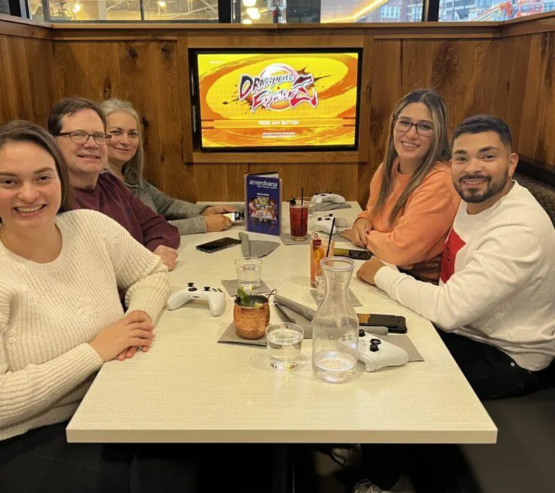 Family sitting at dining table with video game controllers