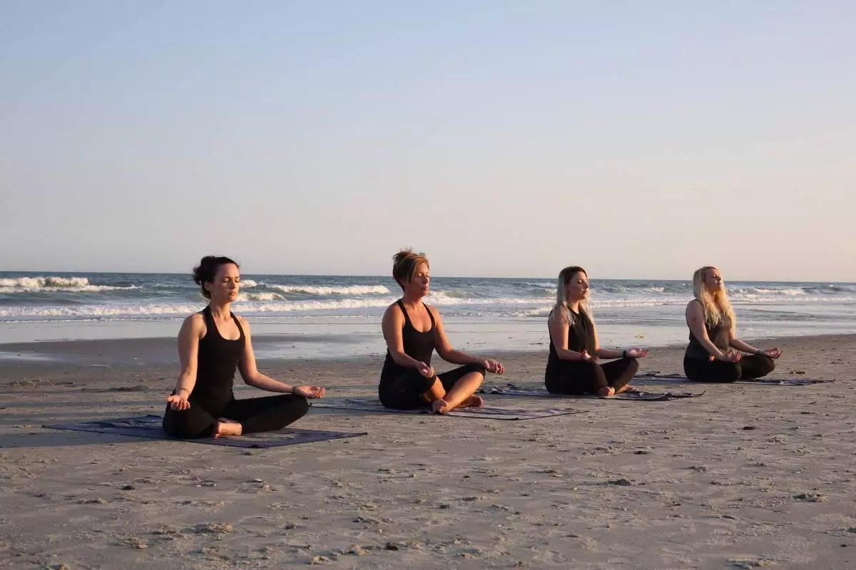 Women practicing yoga on the beach