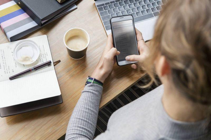 Woman on her phone with laptop nearby