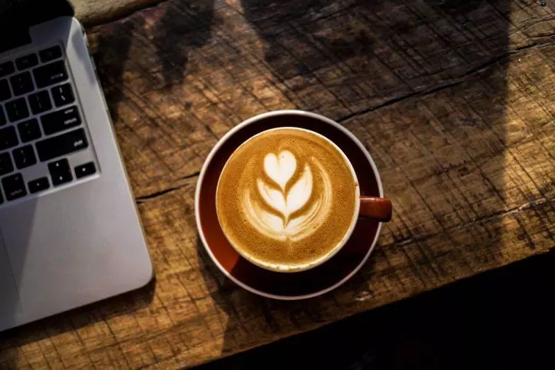 Coffee cup on a wooden table with laptop