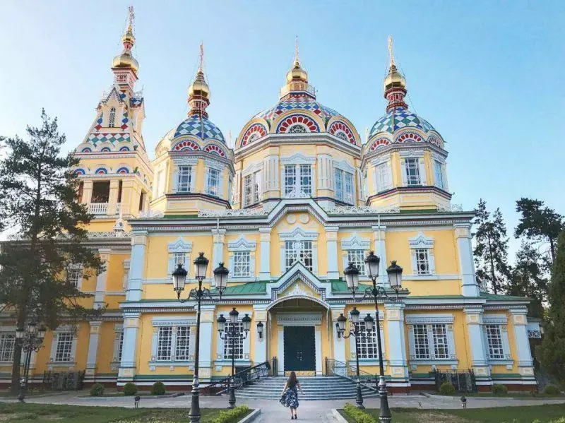 Ornate and bright yellow cathedral with girl walking in front