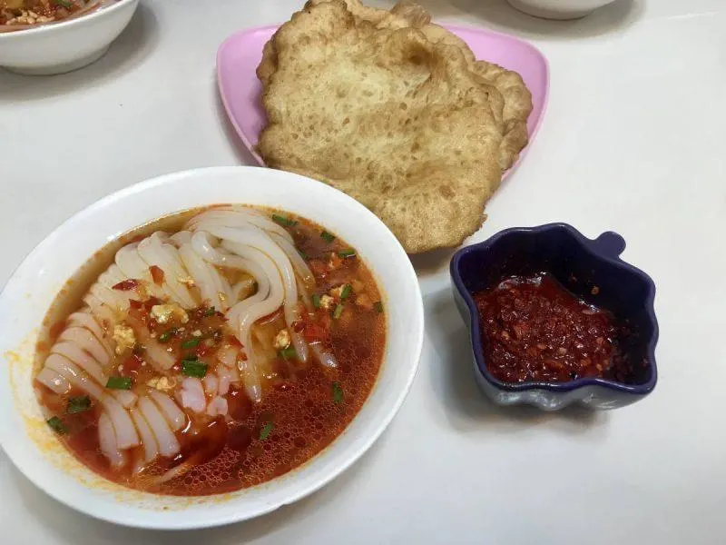 Bowl of ashlan-fu with bread and hot sauce on the side