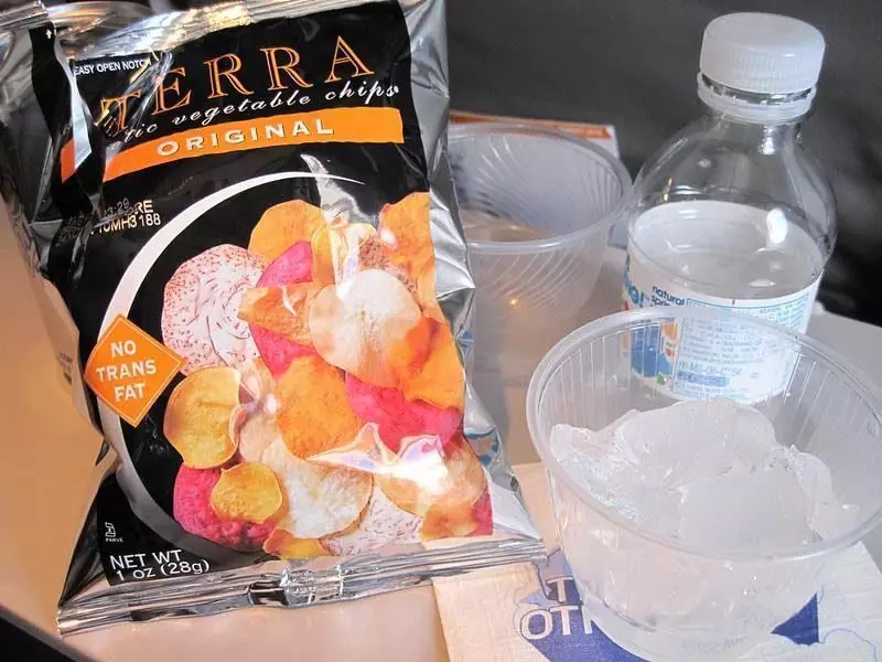 Bag of chips and water on tray table