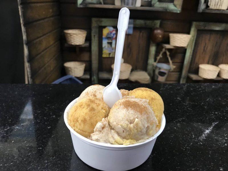 Cup of ice cream with several scoops and spoon in the middle