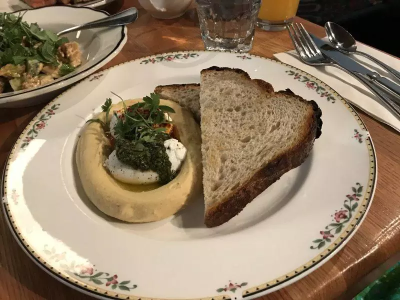 Turkish eggs on a plate with hummus and bread