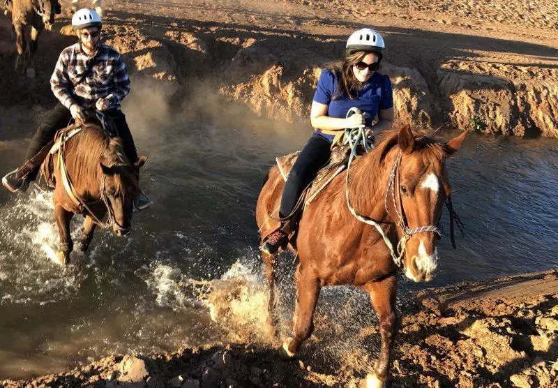 Woman riding a horse across water