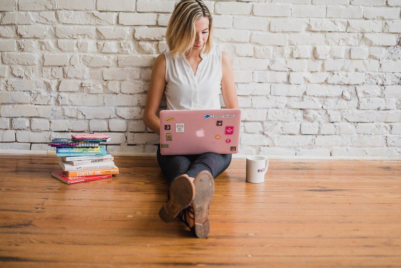 Woman sitting on floor with pink laptop