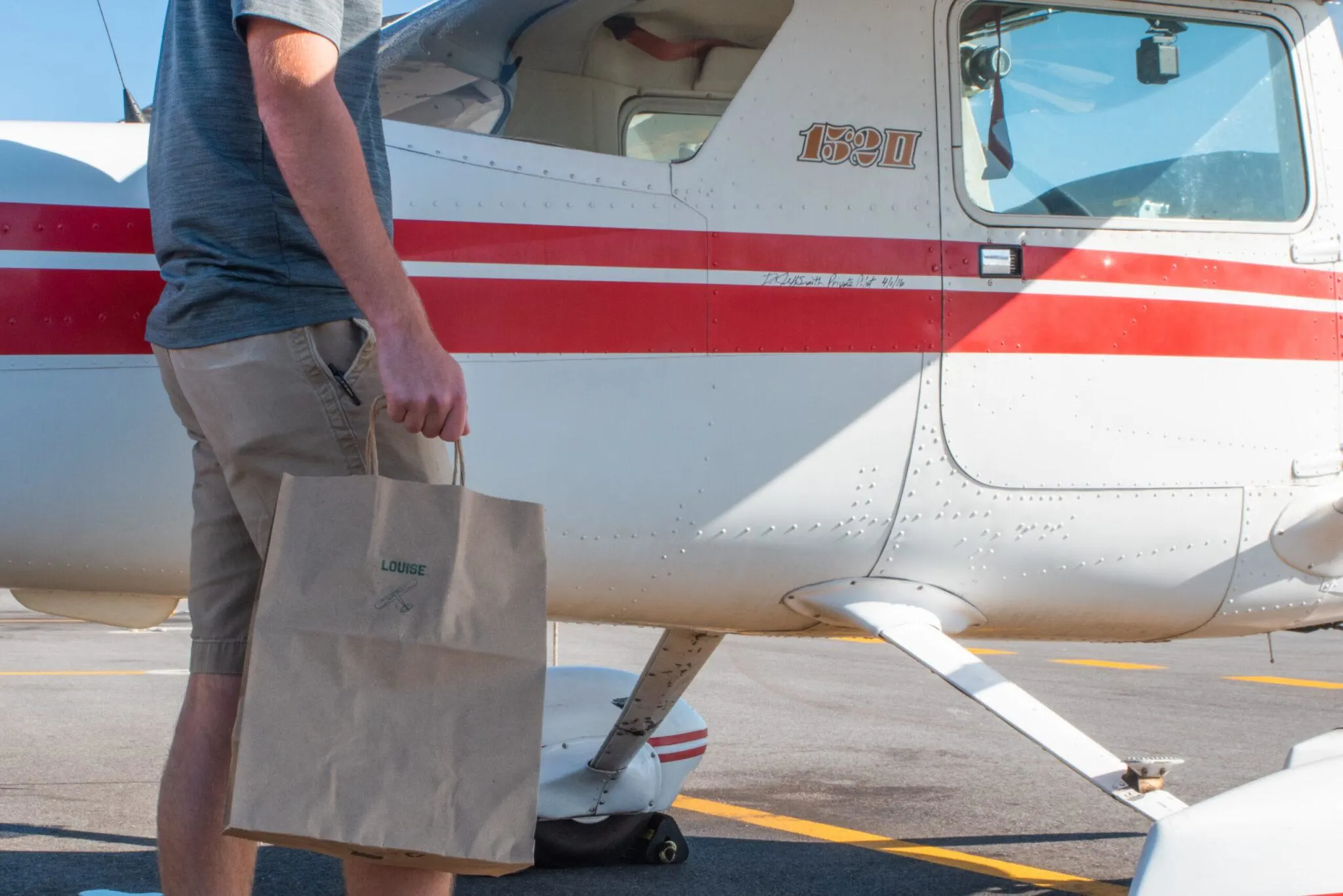 Man carrying paper bag to propeller plane