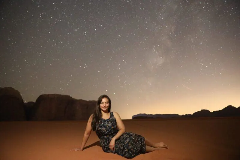 Woman sitting underneath the stars in the desert