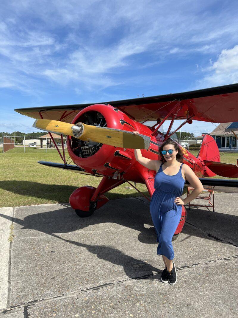 Woman holding propeller of red biplane