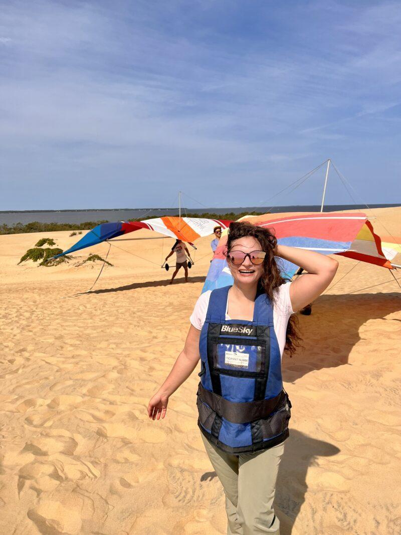 Woman standing in front of hang gliding kites