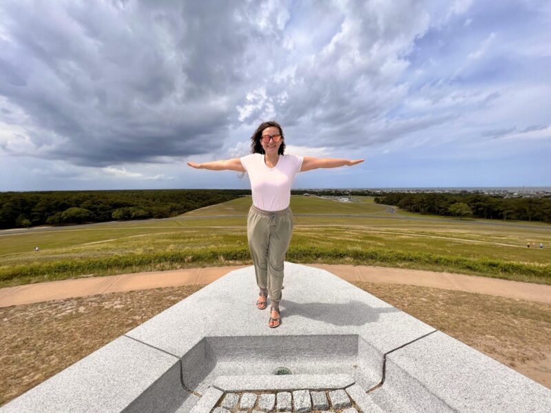 Woman standing with arms open and sky behind her