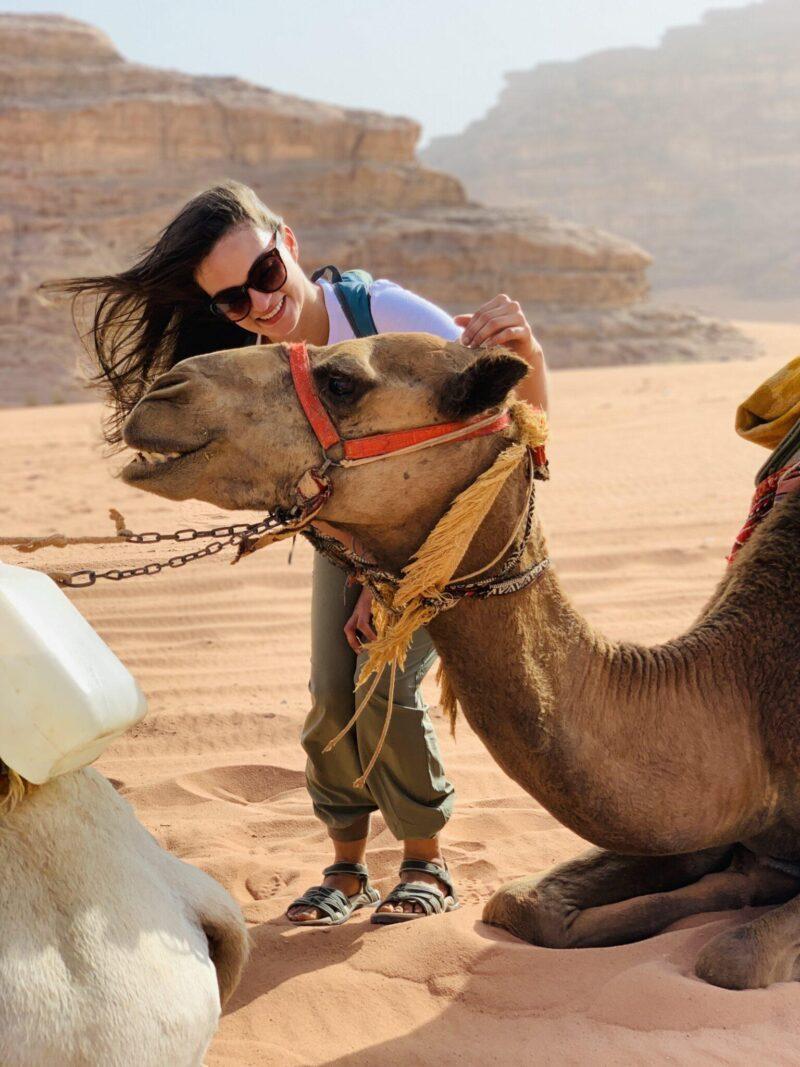 Woman petting sitting camel