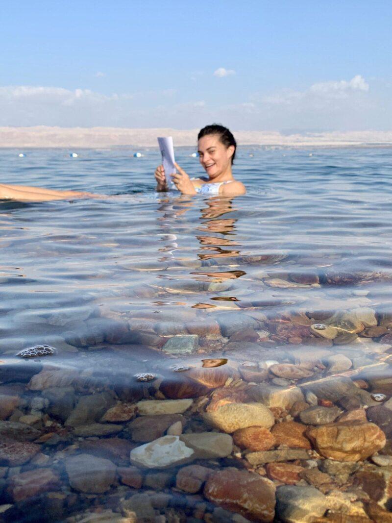 Woman floating in the Dead Sea while reading