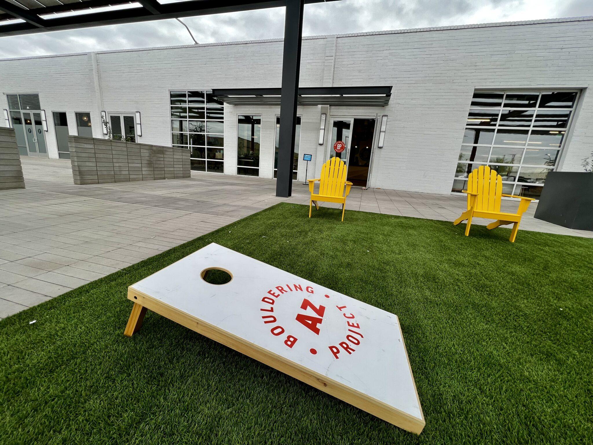 Cornhole on lawn with yellow chairs in background