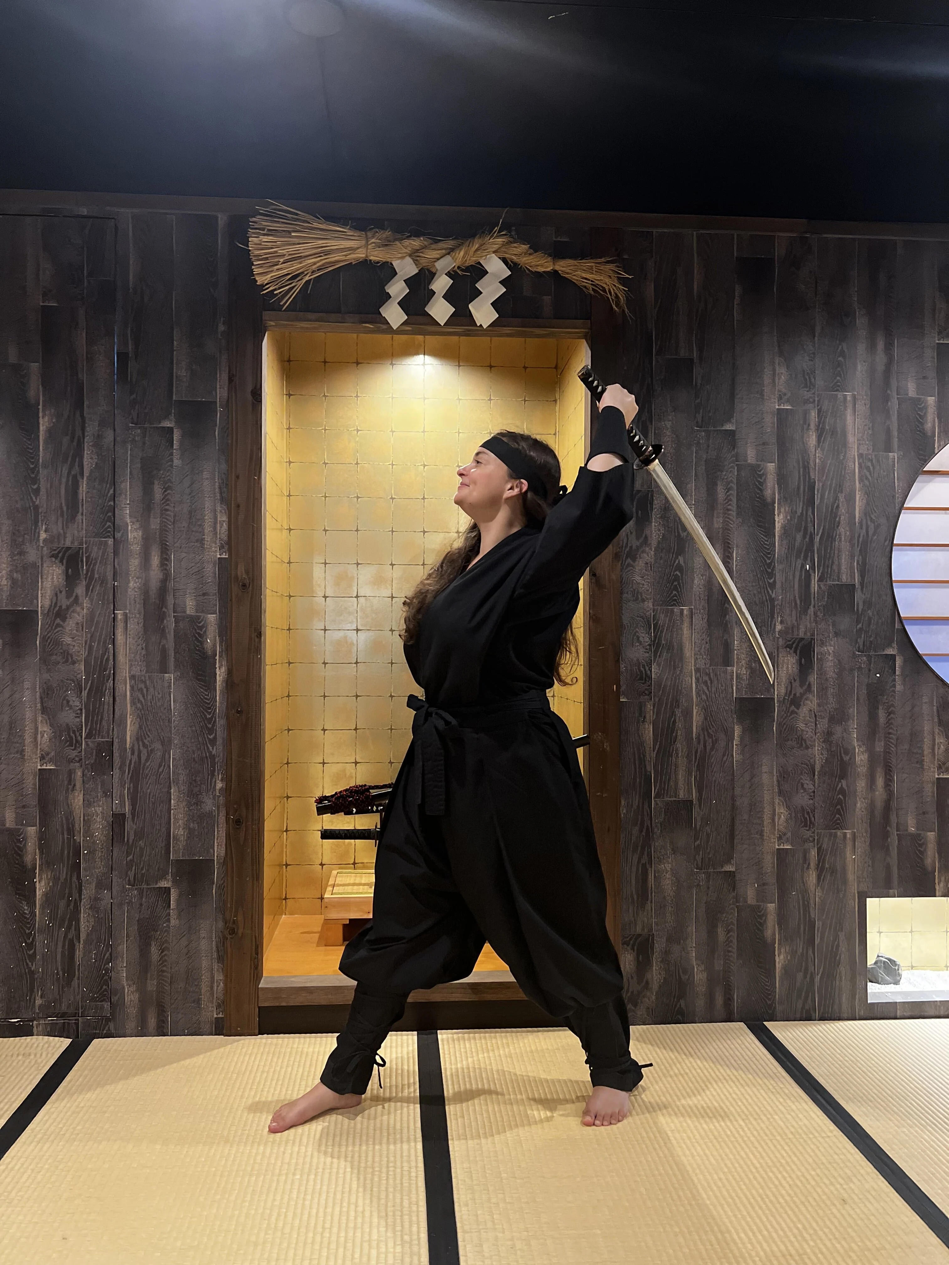 Woman holding katana sword over shoulders