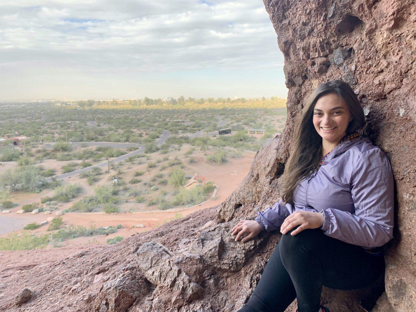 Woman sitting by edge of rock outlook