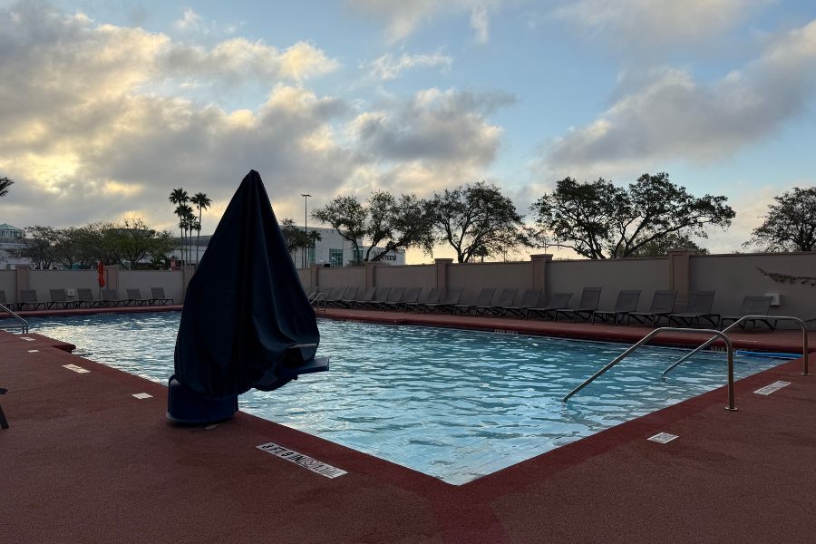 Pool at sunrise with closed umbrella