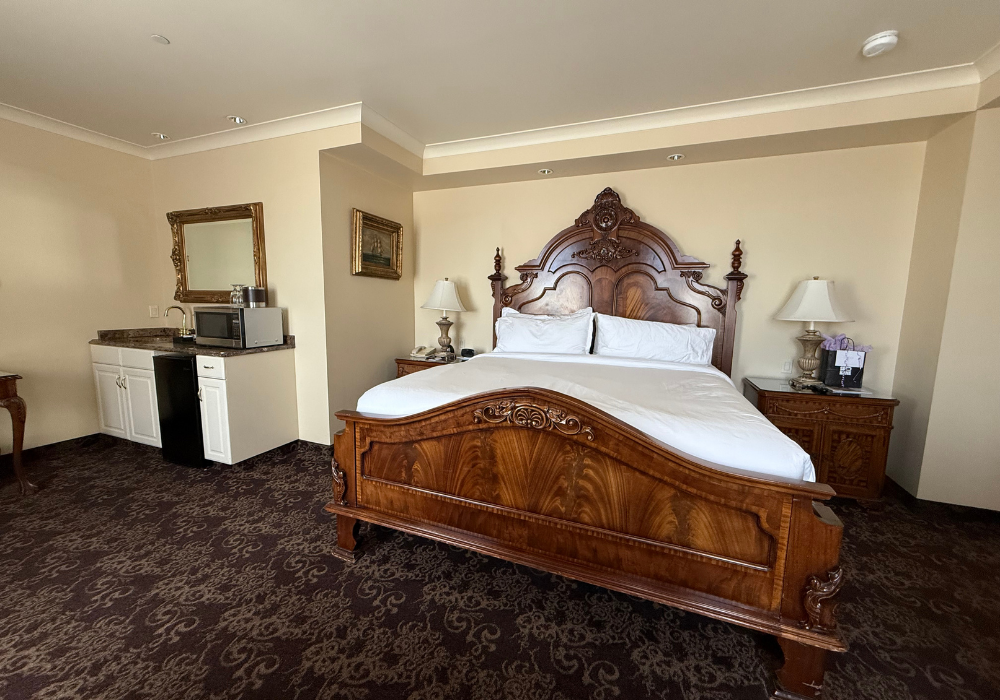Room with wood ing sized bed and kitchenette