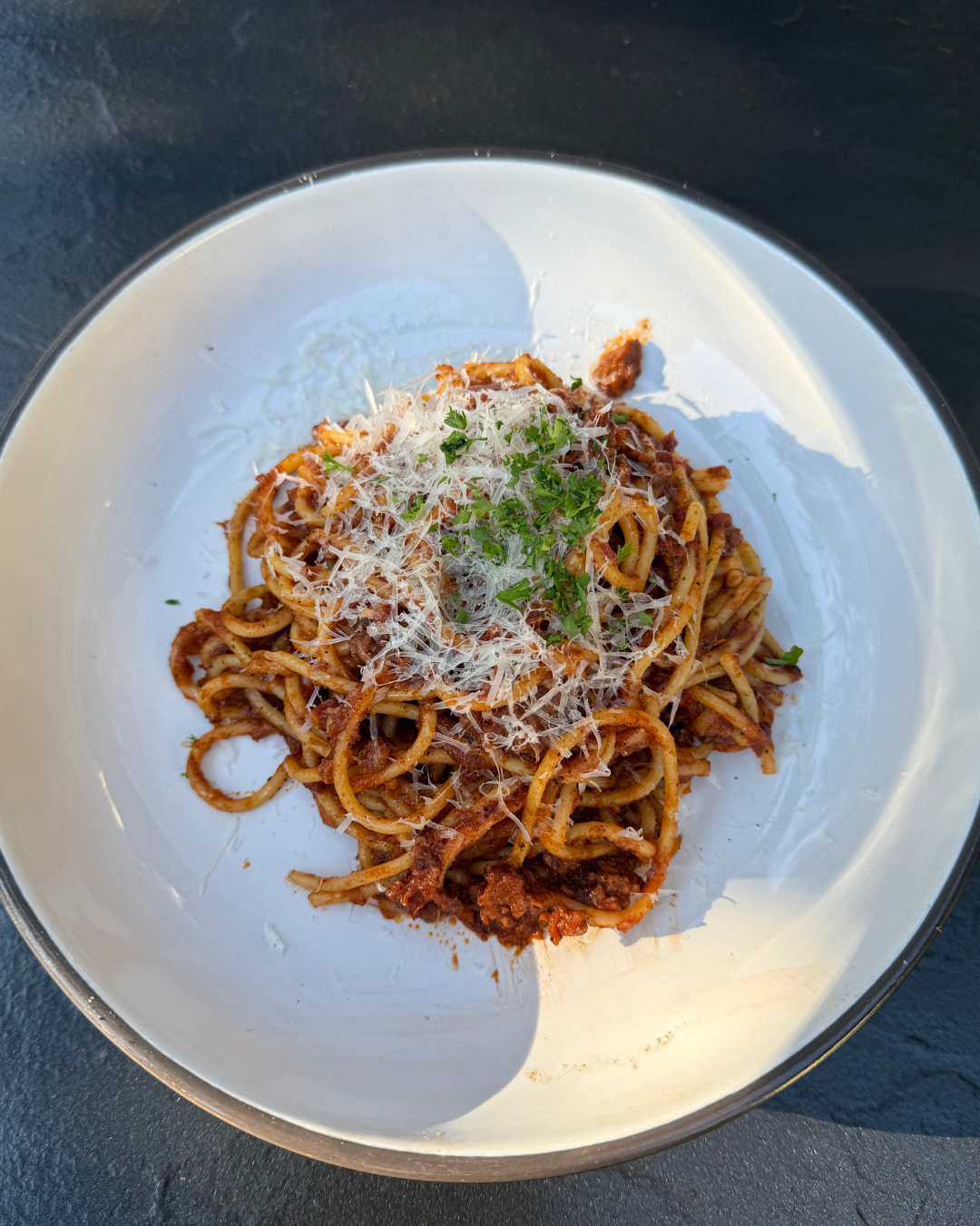 bolognese pasta with cheese and parsley on top