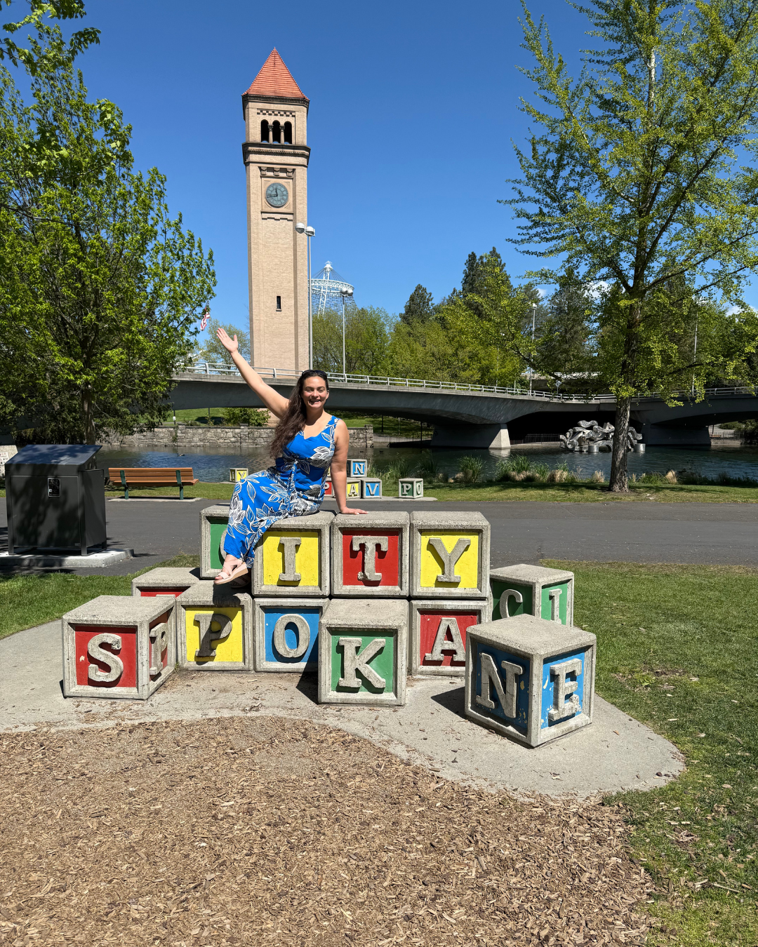 Woman sitting on giant blocks that spell out "City of Spokane"