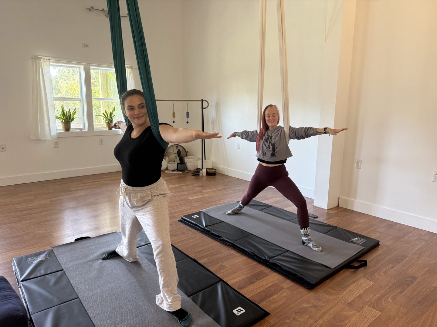 Two women stretching during aerial yoga