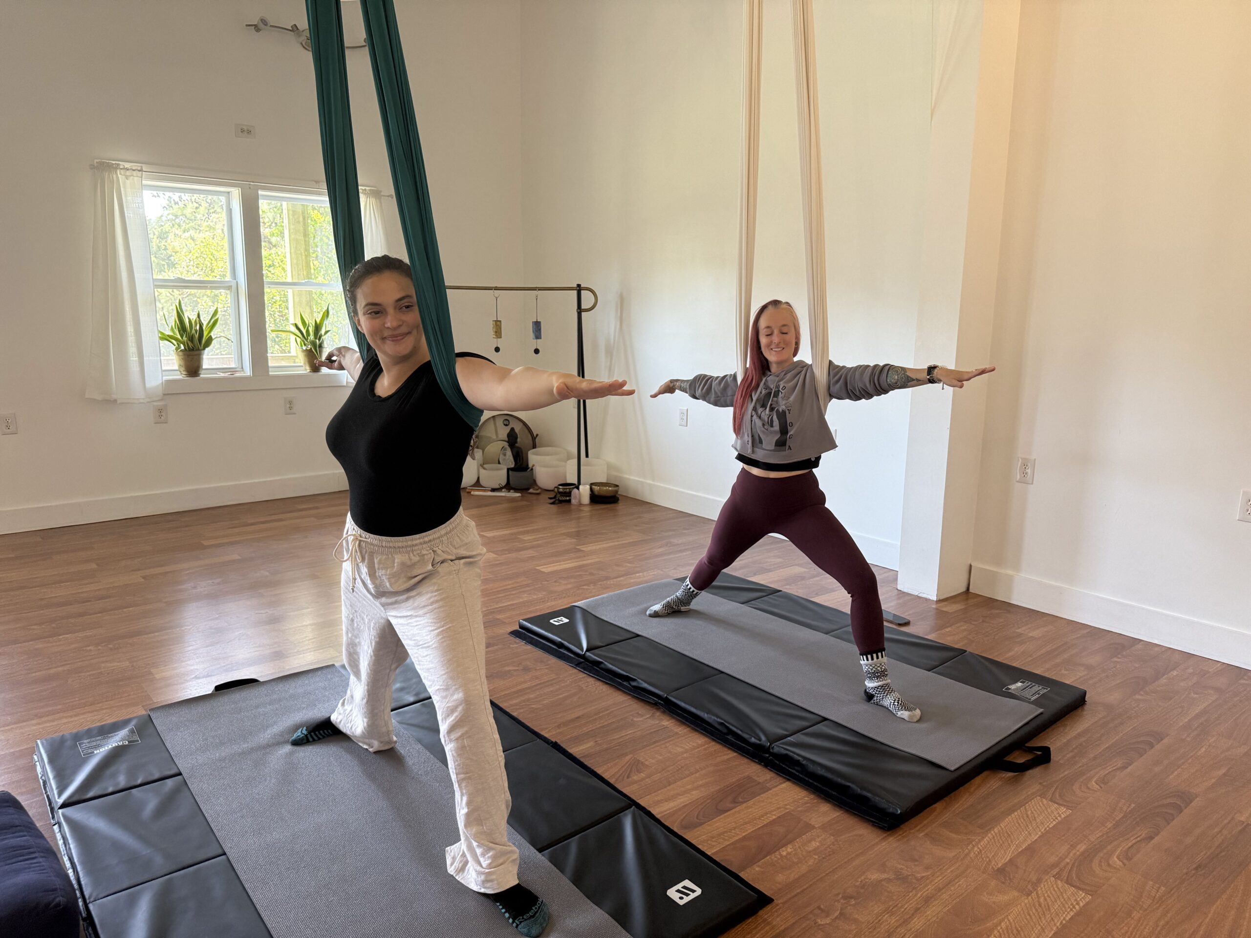 Two women stretching during aerial yoga
