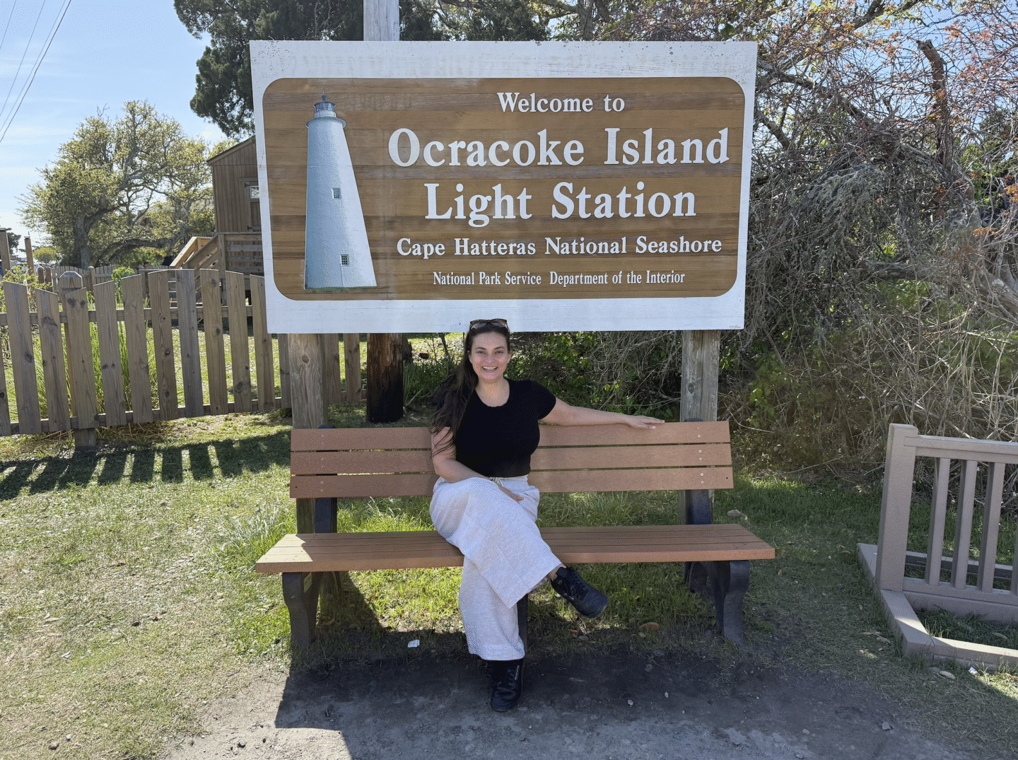 Woman sitting in front of Ocracoke Light Station sign
