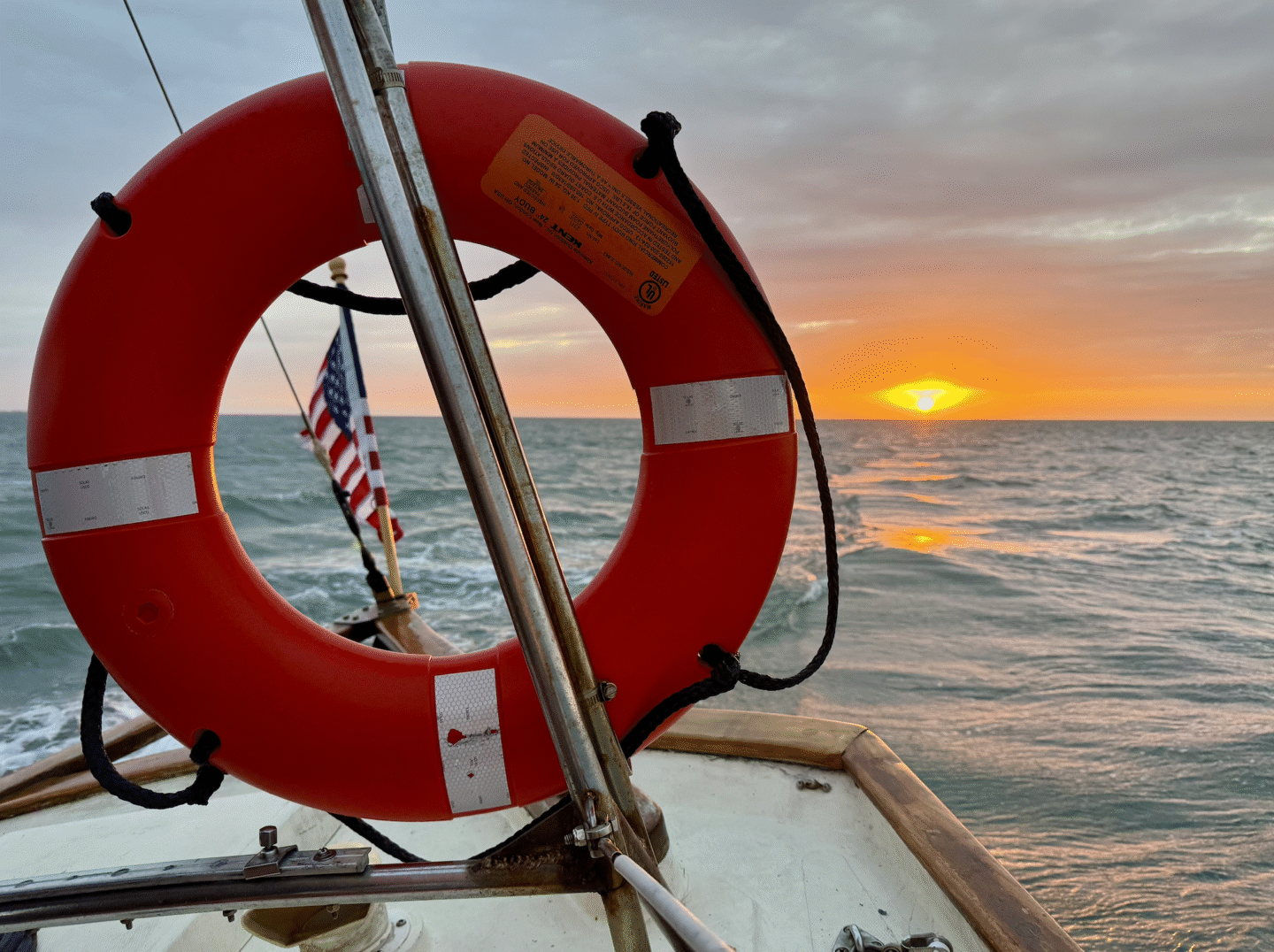 Boat sailing into the sunset with a life ring in center